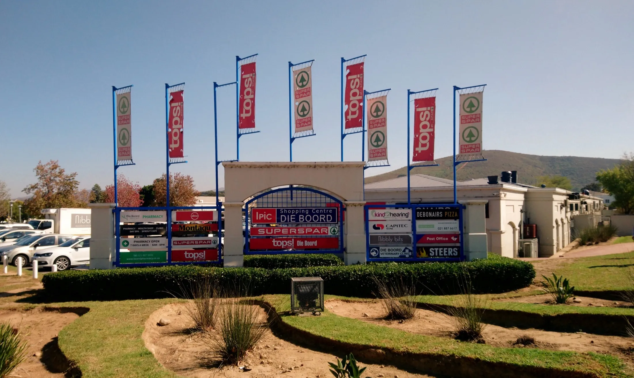 The entrance pylon of Ipic Shopping Centre Die Boord in Stellenbosch, with the tenant boards and Tops flags.